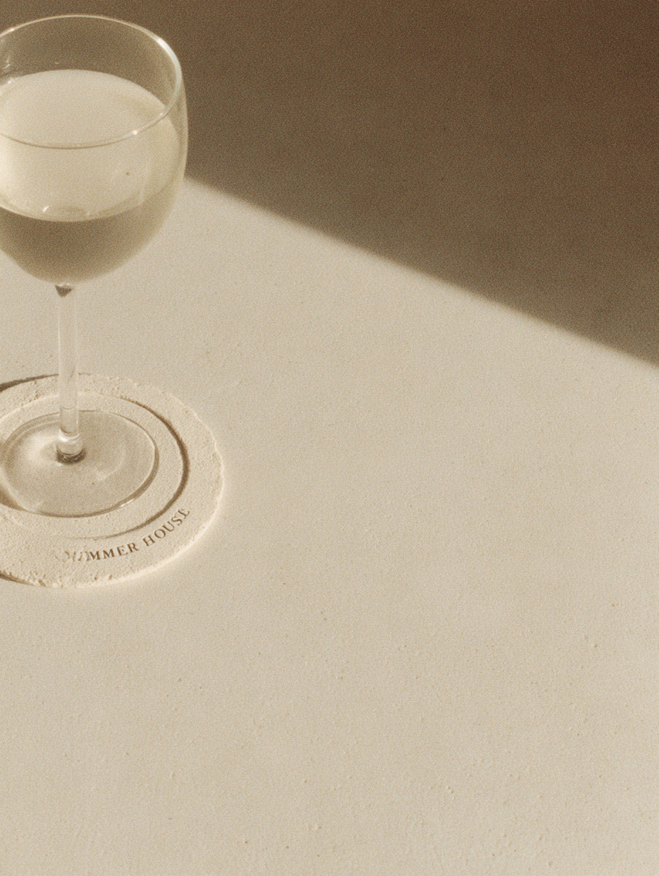 Minimalist editorial photo of a champagne glass casting soft shadow on beige surface — MakeStories.com