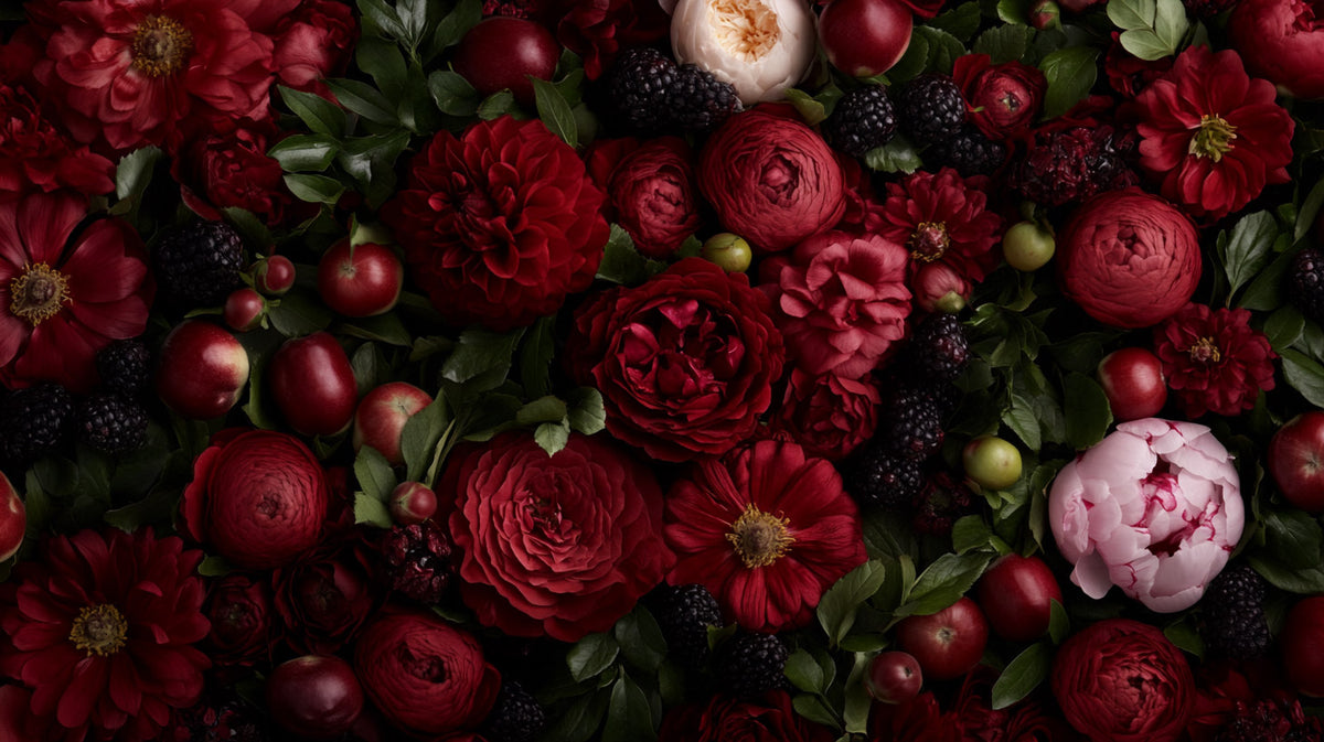 Editorial flat lay of dark red roses, peonies, blackberries, and apples arranged with green leaves — MakeStories.com