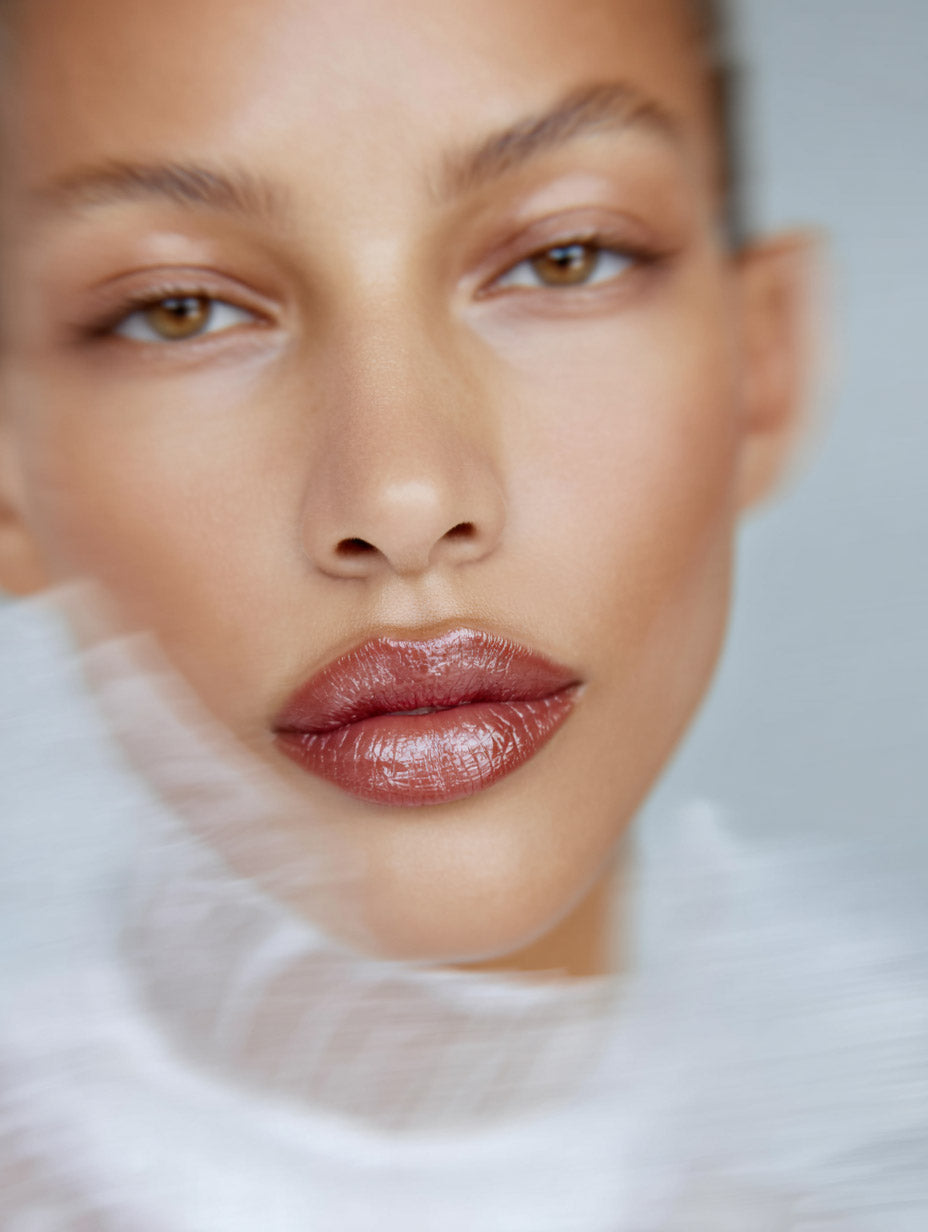 Editorial beauty close-up of woman with glossy brown lipstick and soft focus detail — MakeStories.com