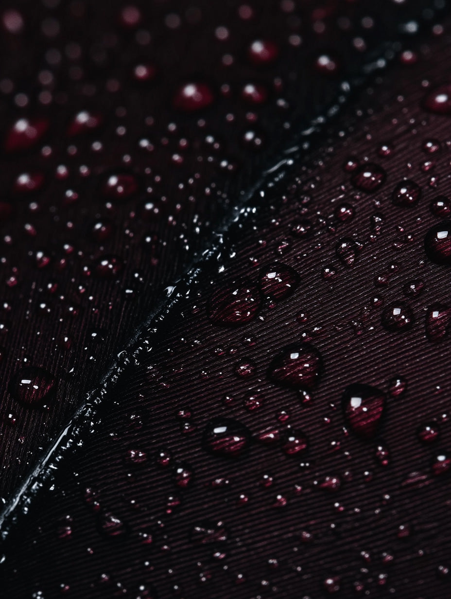 Detailed macro close-up of a dark feather covered in water droplets with rich texture and shine.
