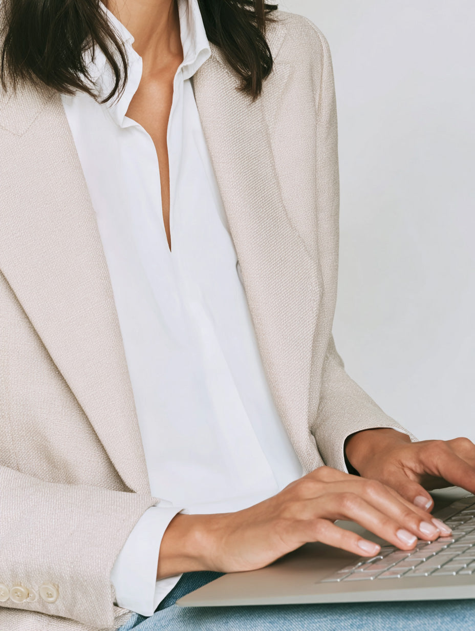 Faceless content business woman in beige blazer white blouse typing on her laptop