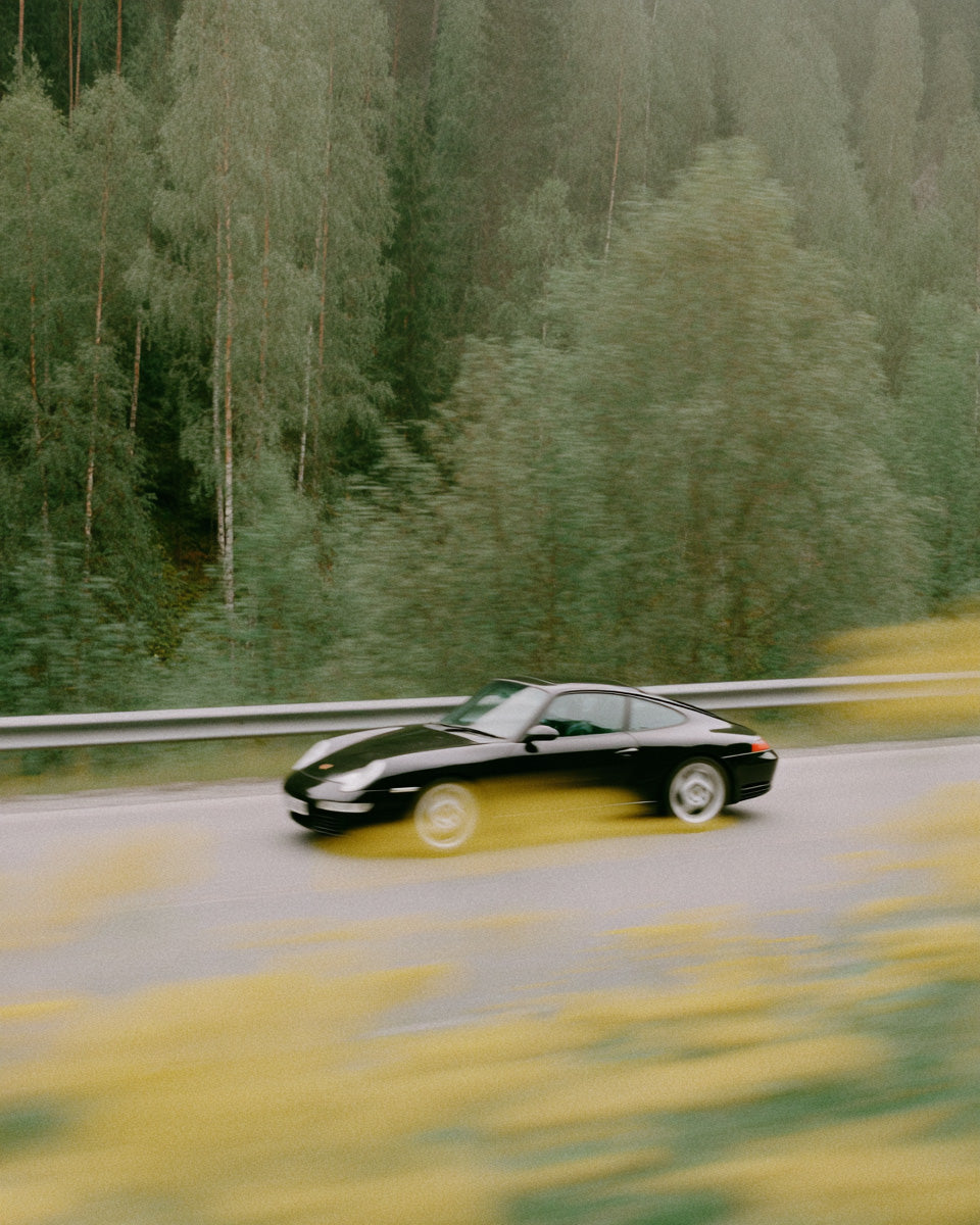 black luxury sports car driving fast on forest road